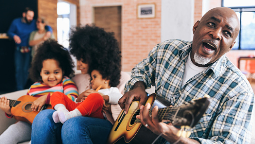 Man playing the guitar for his daughter and grandkids